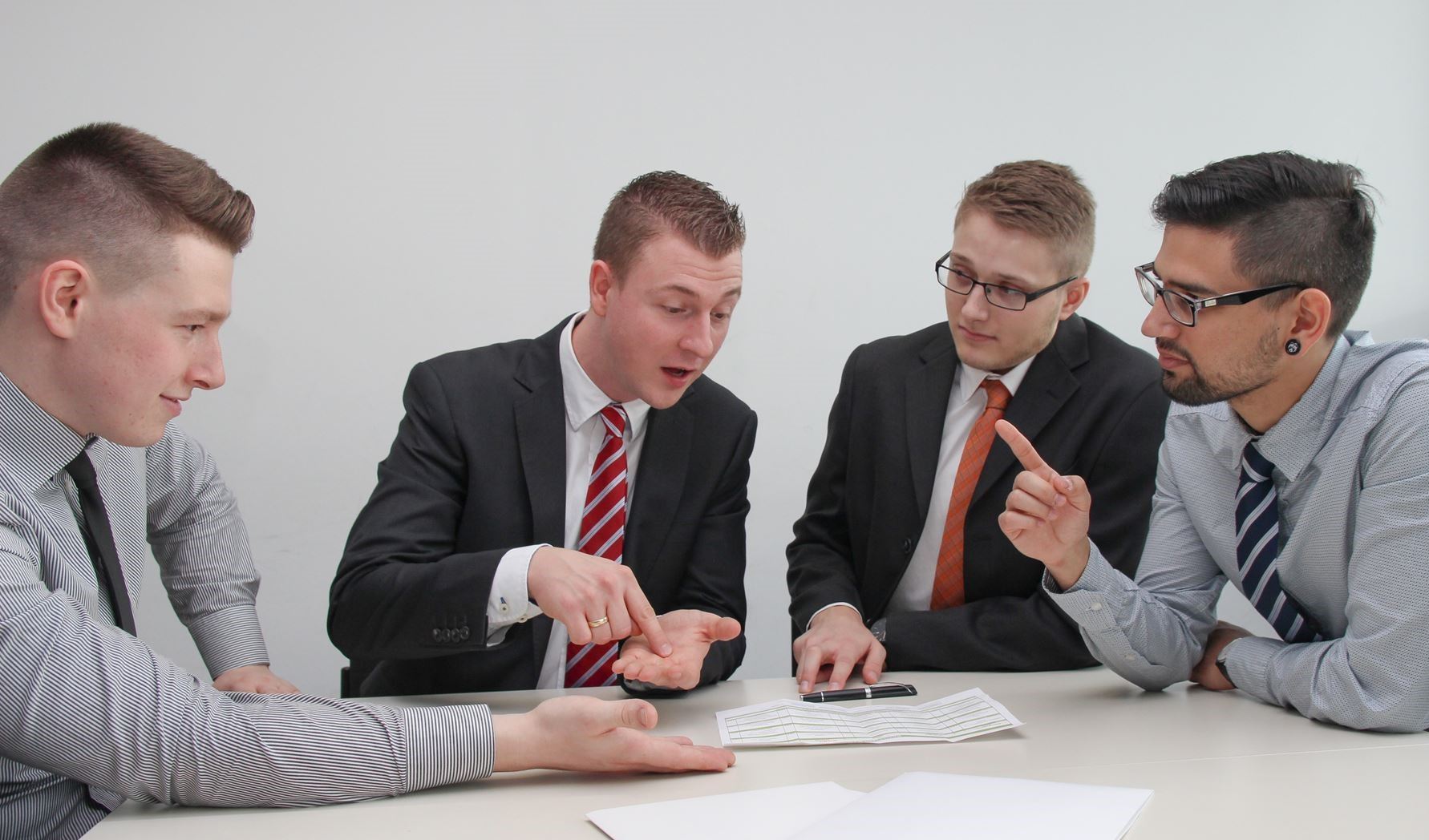 group of people sitting around a table discussing with each other