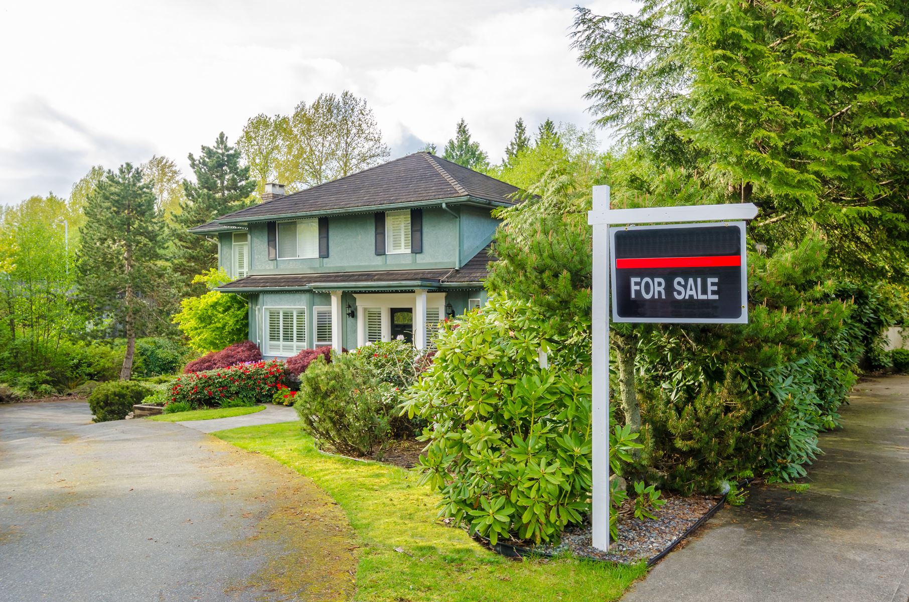 House with a for sale sign in the front yard