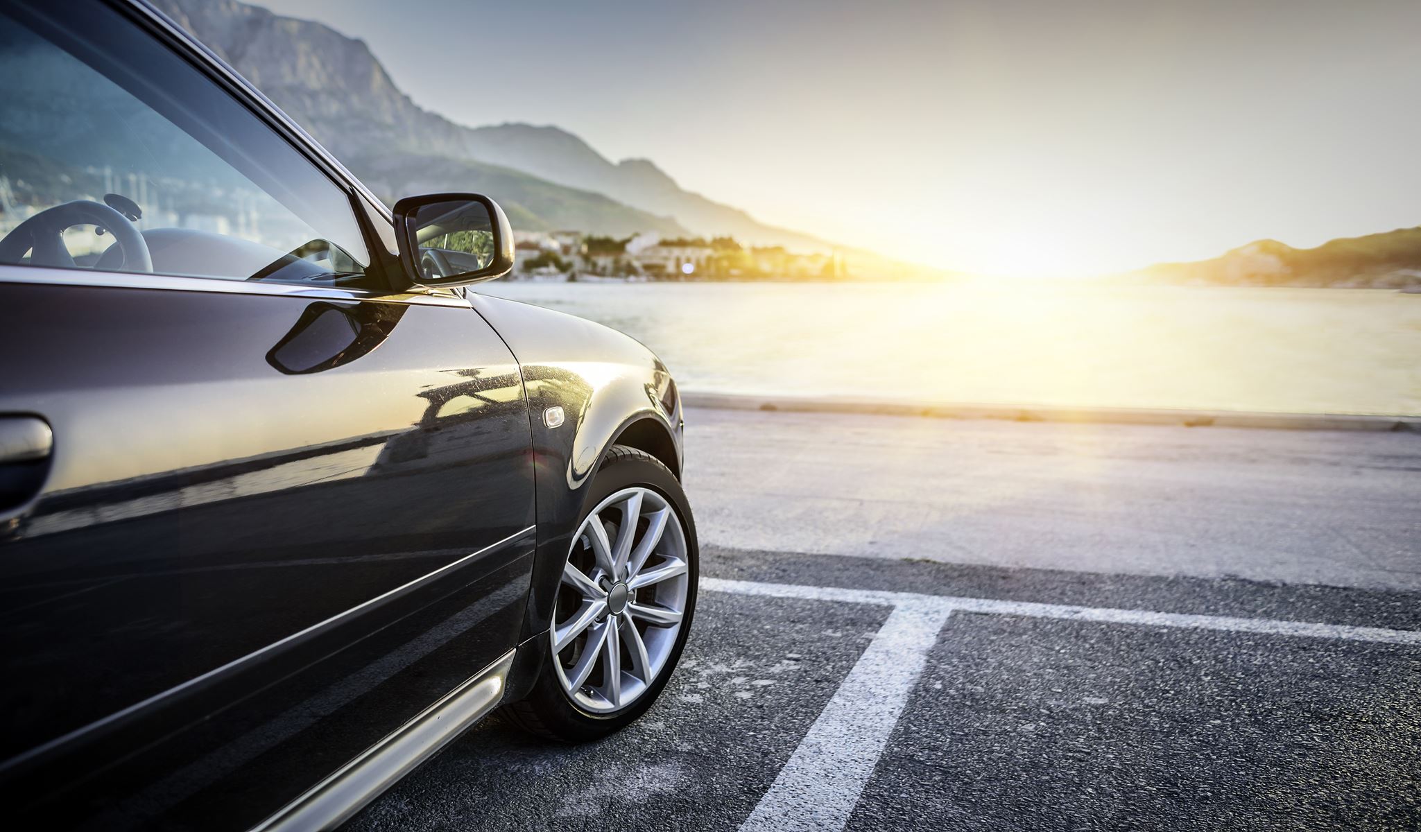 car parked by the ocean during sunset