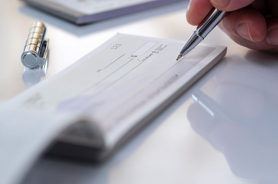 Close up of check book and pen writing a check