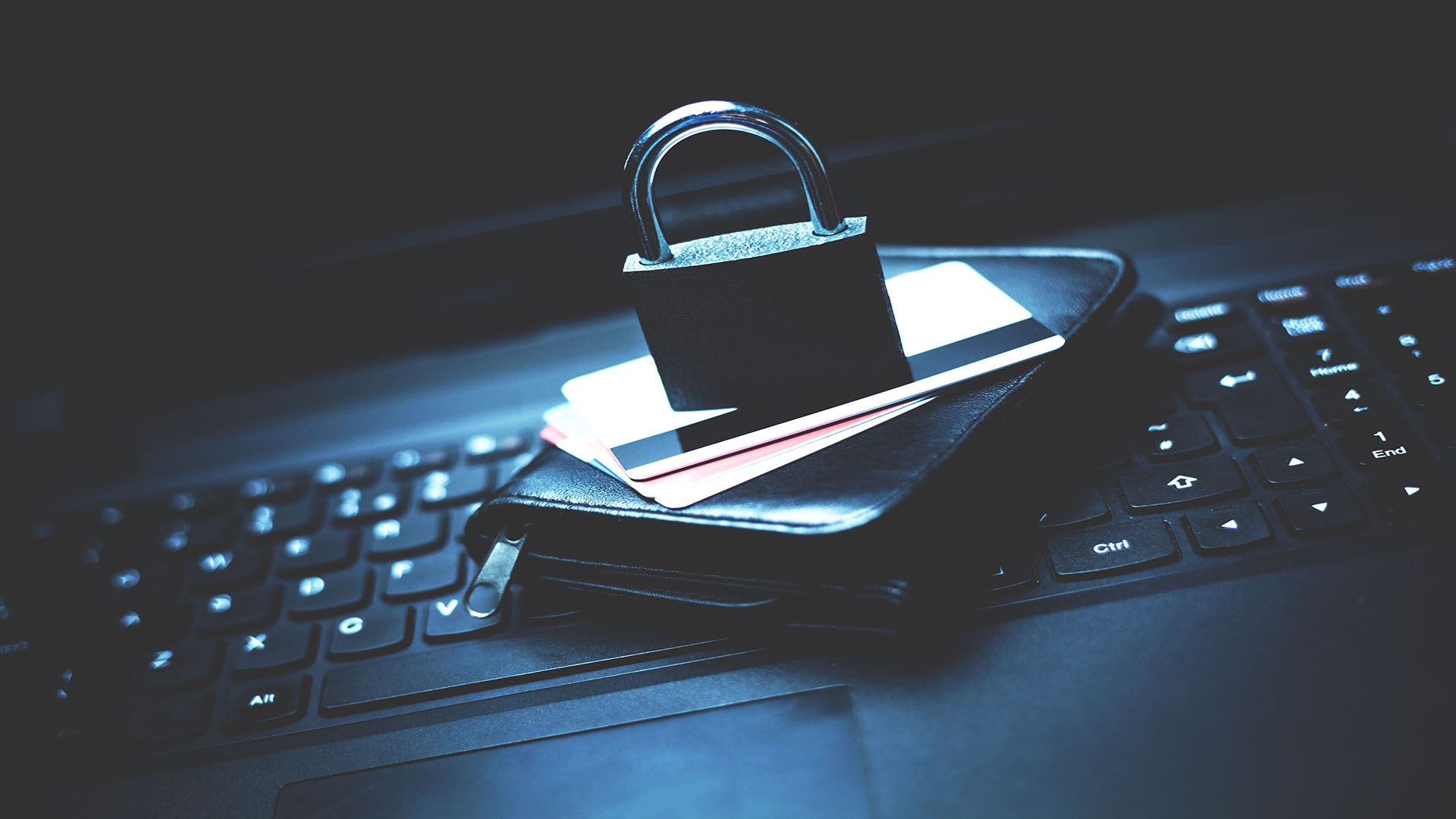 padlock sitting on credit cards, a wallet, and a computer keyboard